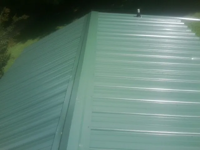 New green metal panels meeting at the ridge of a roof — Flat Roof Repair work by our crew in Vermilion