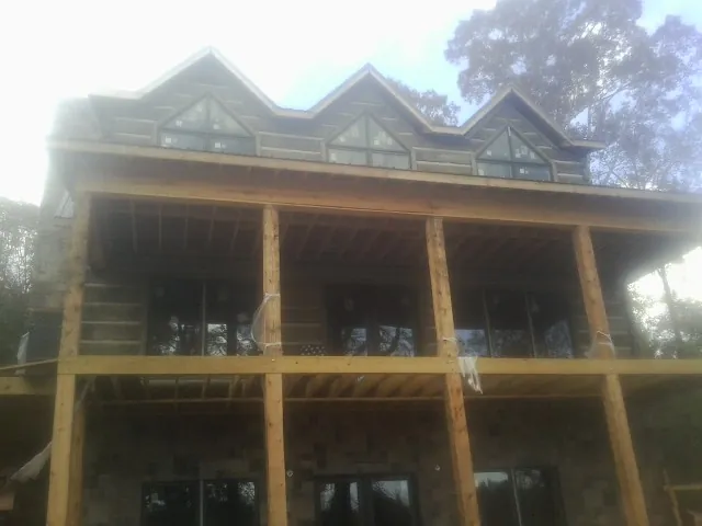 Dormers and porch framing on a large log home under construction — Roof Coating work by our crew in Vermilion