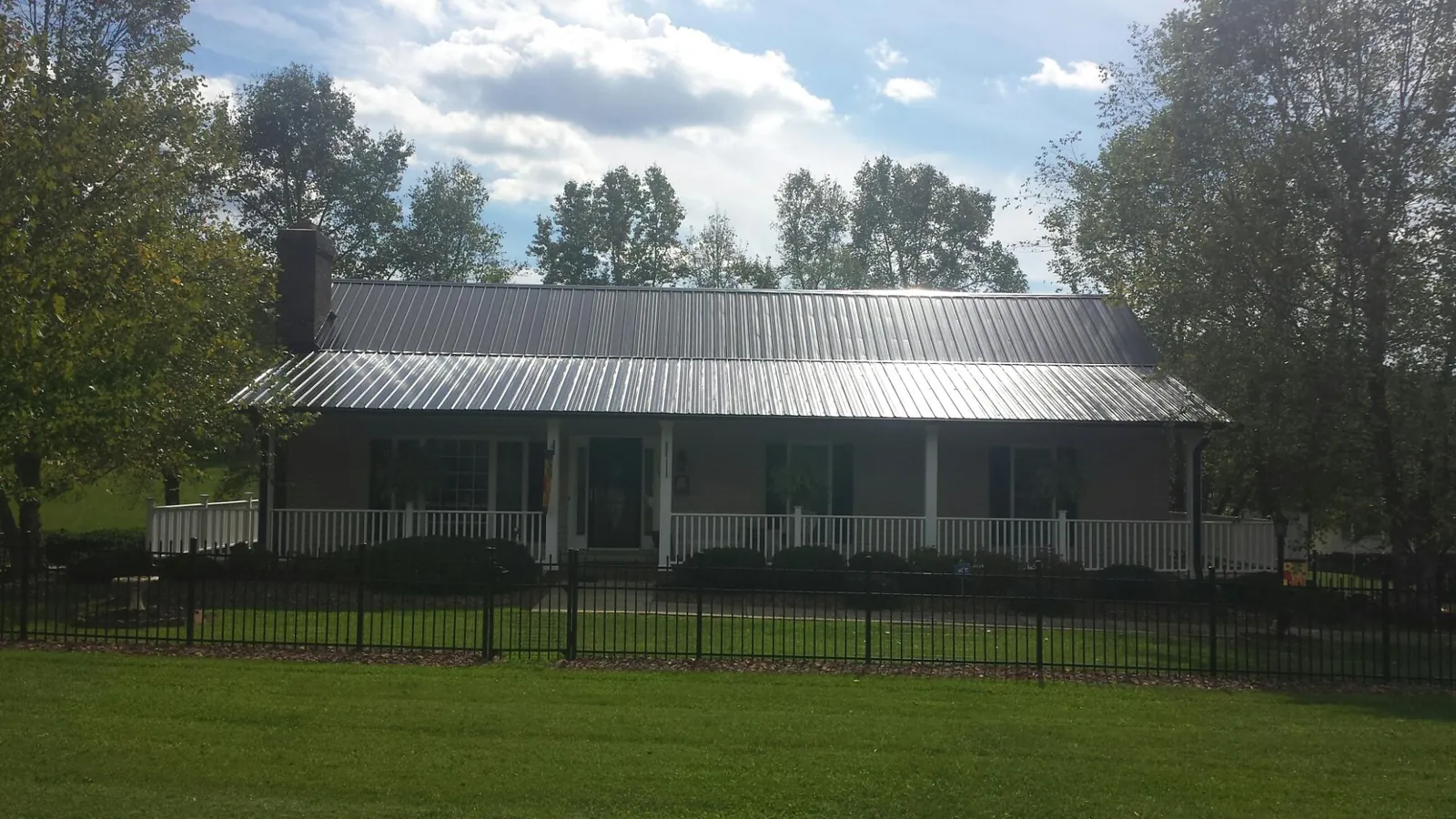 Gray metal roof on a brick ranch with a full width front porch — Gutter Guard Installation work by our crew in Vermilion