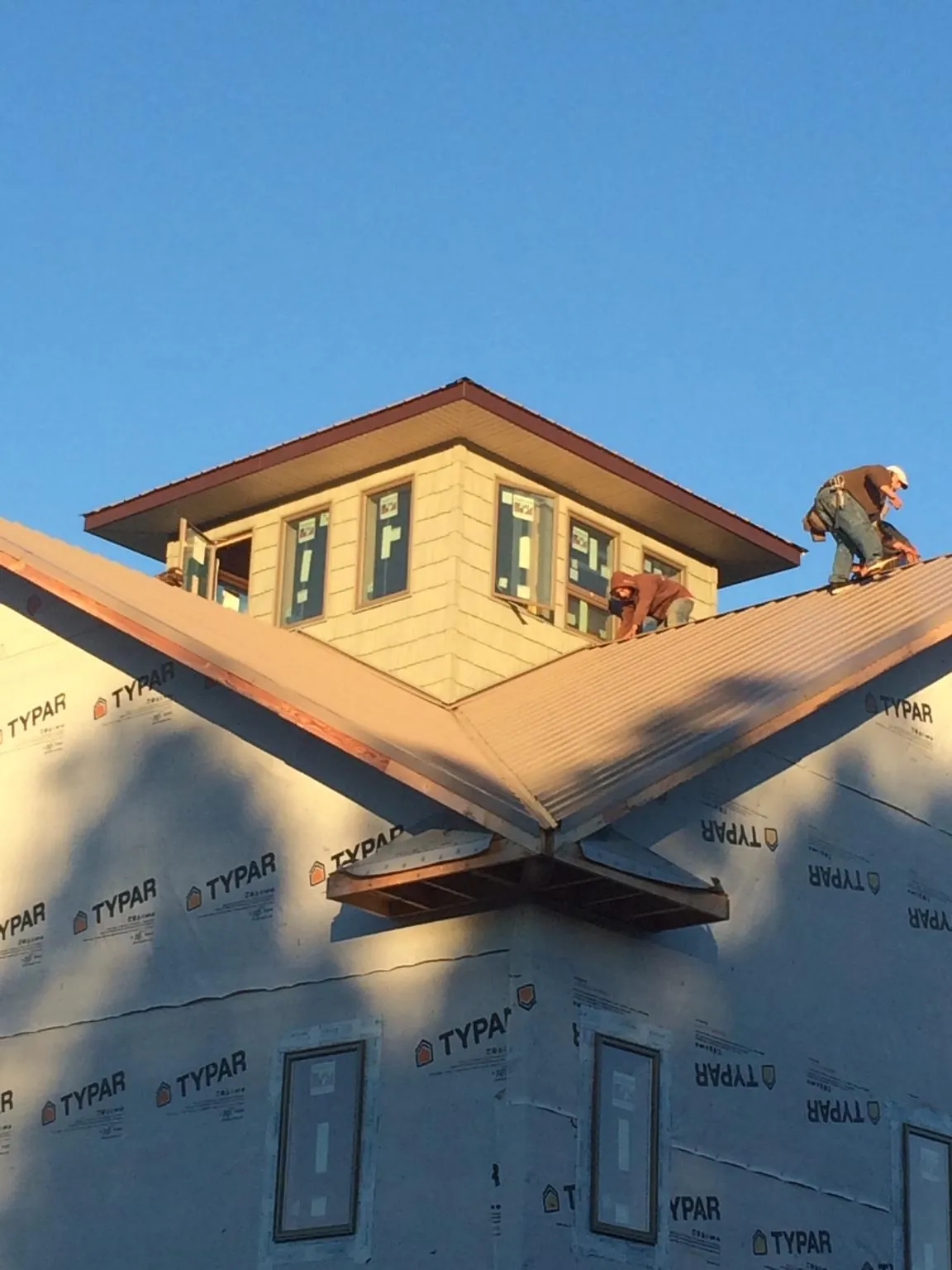 Roofers working around a rooftop cupola on a new metal roof at sunset — Roof Waterproofing in Vermilion by Roofing Brothers
